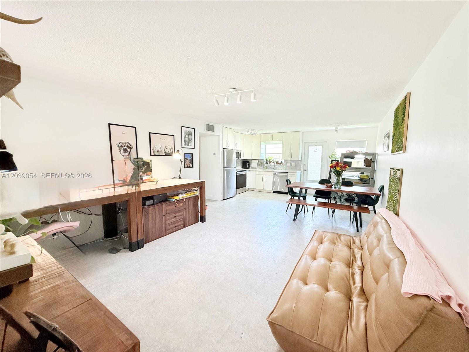 An open-concept living and dining area features a kitchen, light tile floors, and white walls — 1722 Mayo St # 105, Hollywood FL 33020, HOLLYWOOD, FL