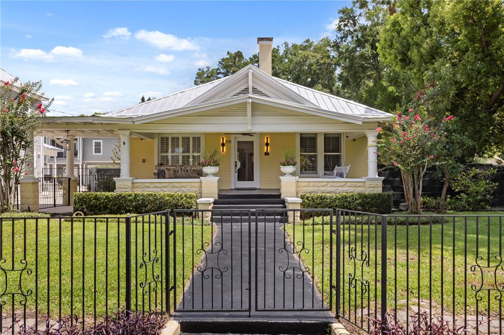 A yellow bungalow with a metal roof, front porch, and black metal fence — 209 E AMELIA STREET, ORLANDO, FL