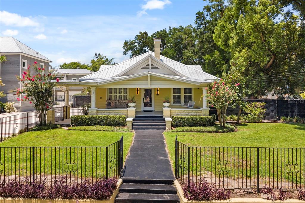 A yellow bungalow with a metal roof, front porch, and black metal fence — 209 E AMELIA STREET, ORLANDO, FL