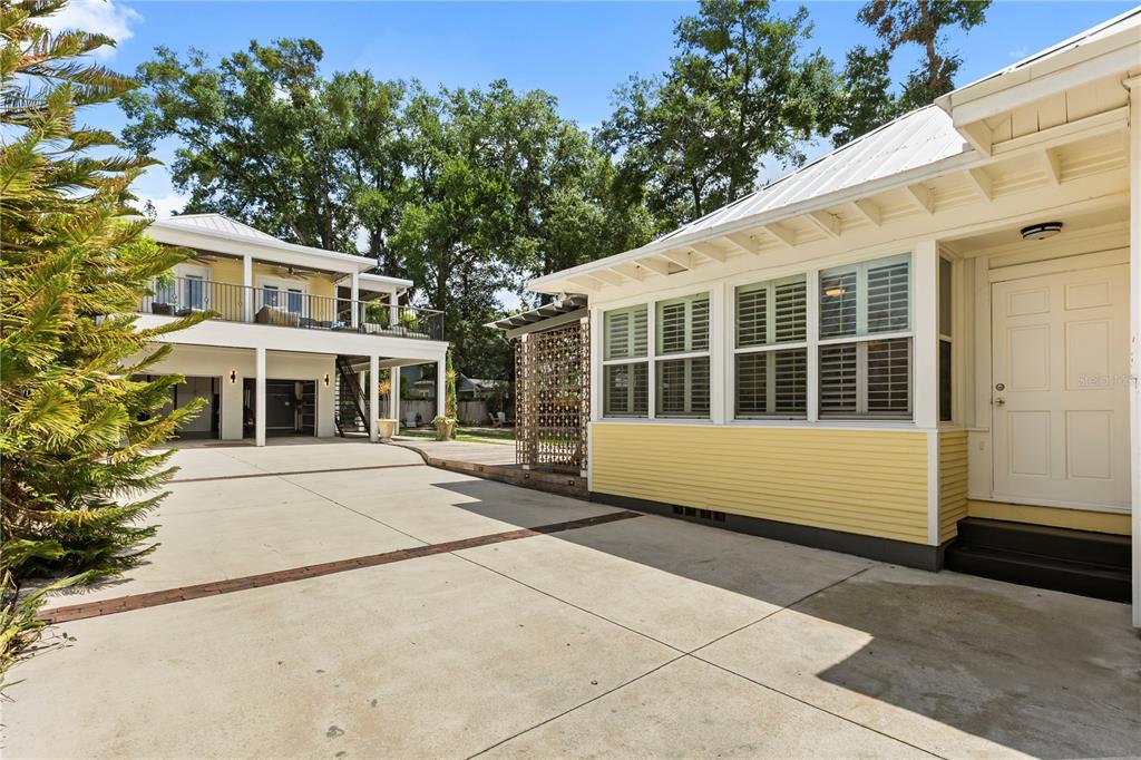 A concrete driveway leads to a yellow house and a two-story detached garage structure — 209 E AMELIA STREET, ORLANDO, FL