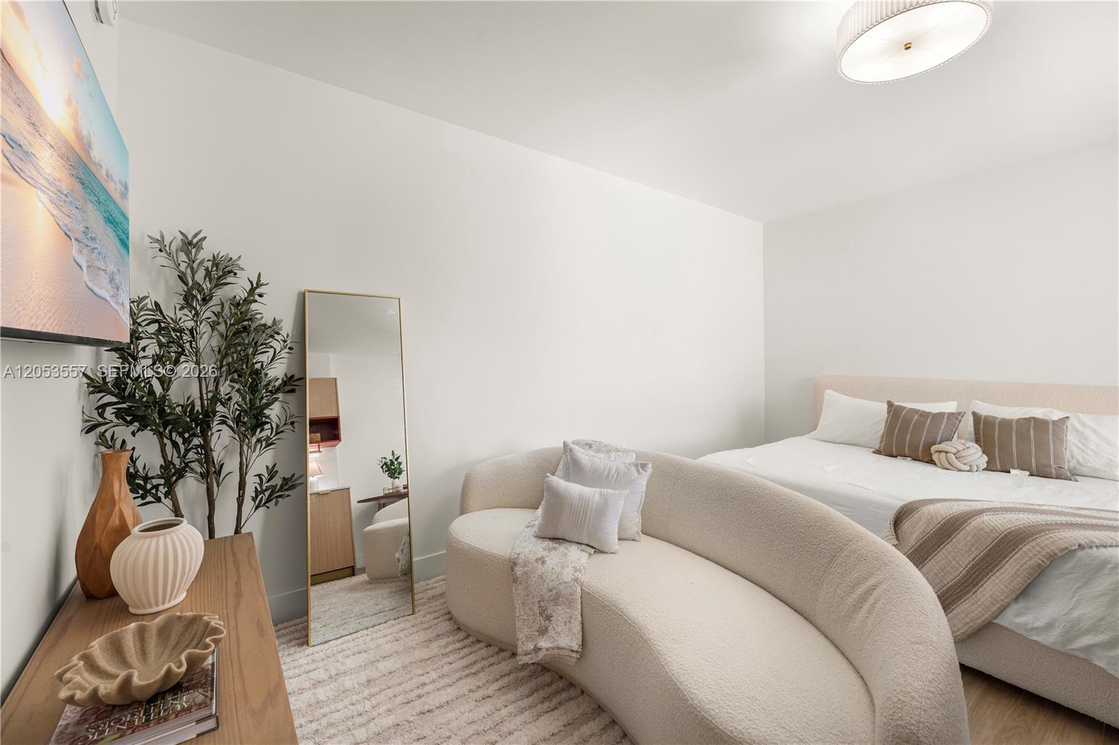 A bedroom features a curved sofa, a floor mirror, a bed, and a wall-mounted television — 90 NE 32 St # 715, Miami FL 33127, MIAMI, FL