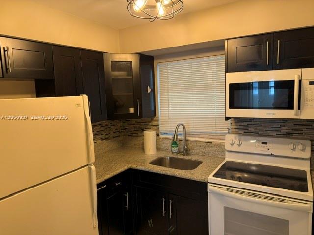 A kitchen features dark wood cabinets, a white refrigerator, a microwave, and a stainless sink — 1859 Wiley St # 3, Hollywood FL 33020, HOLLYWOOD, FL