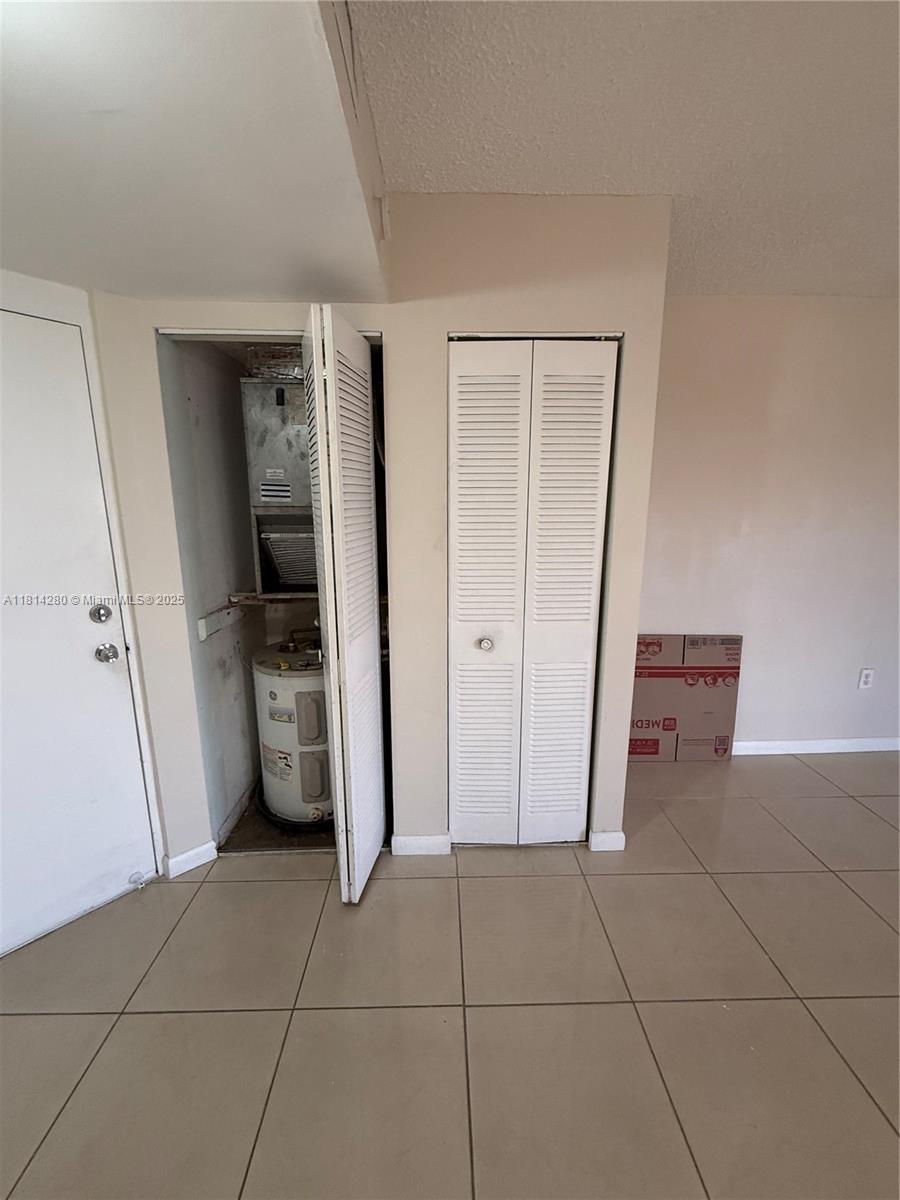 A room features tiled floors, a white door, and two closets, one containing a water heater — 8255 SW 152 AV # 2, Miami FL 33193, MIAMI, FL