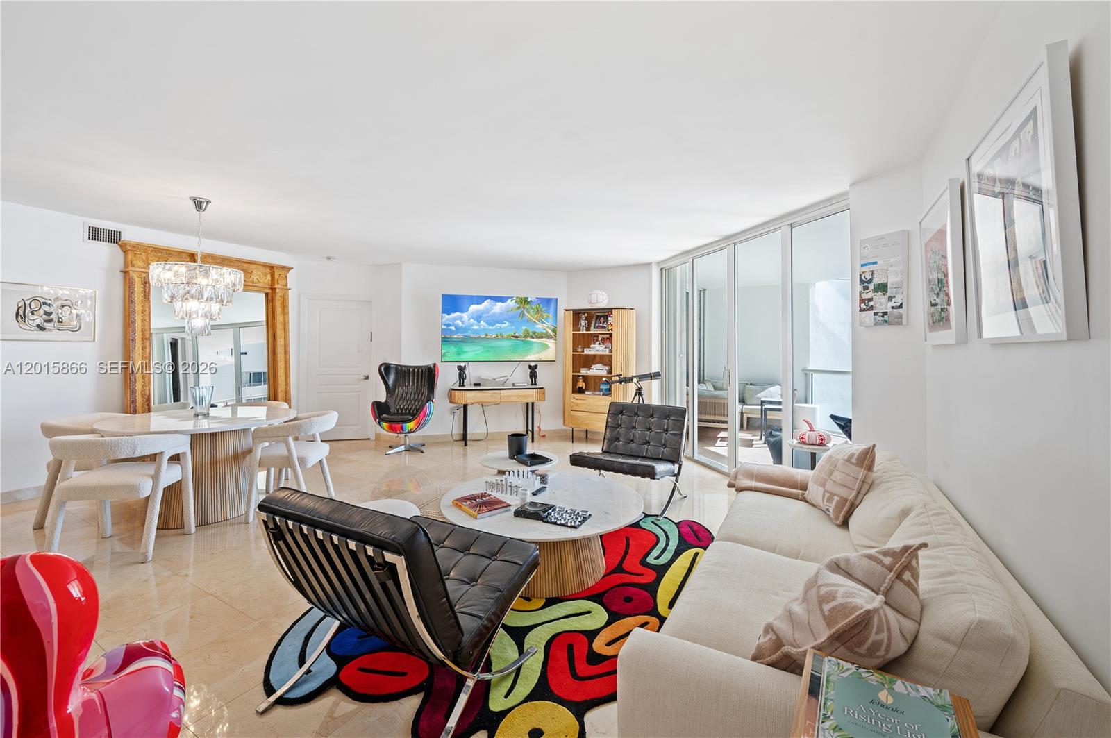 A modern living and dining area features a colorful rug, marble floors, and floor-to-ceiling windows — 8925 Collins Ave # 9J, Surfside FL 33154, SURFSIDE, FL