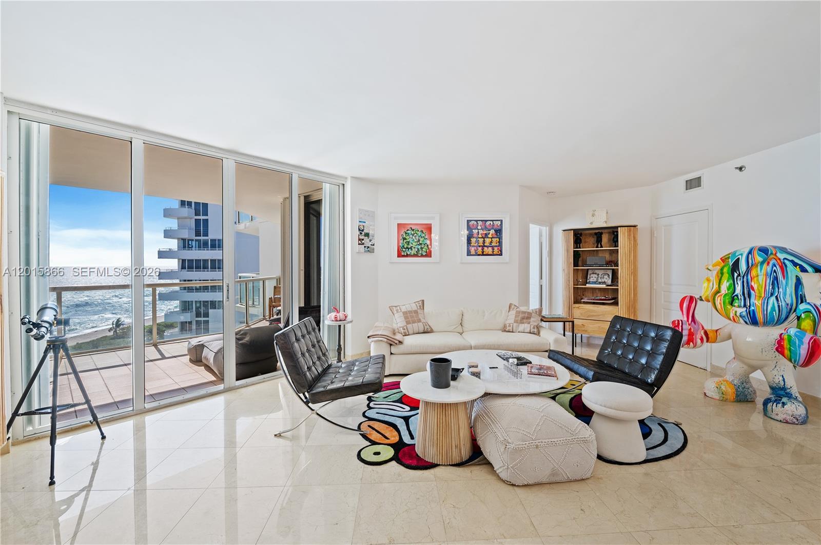 A modern living room features a white sofa, black leather chairs, and a colorful rug — 8925 Collins Ave # 9J, Surfside FL 33154, SURFSIDE, FL