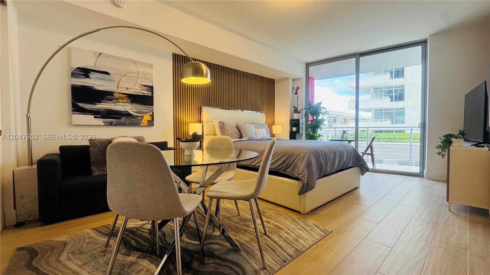 A studio apartment features a bed, dining set, sofa, and a balcony with outdoor views — 90 NE 32 St # 613, Miami FL 33137, MIAMI, FL