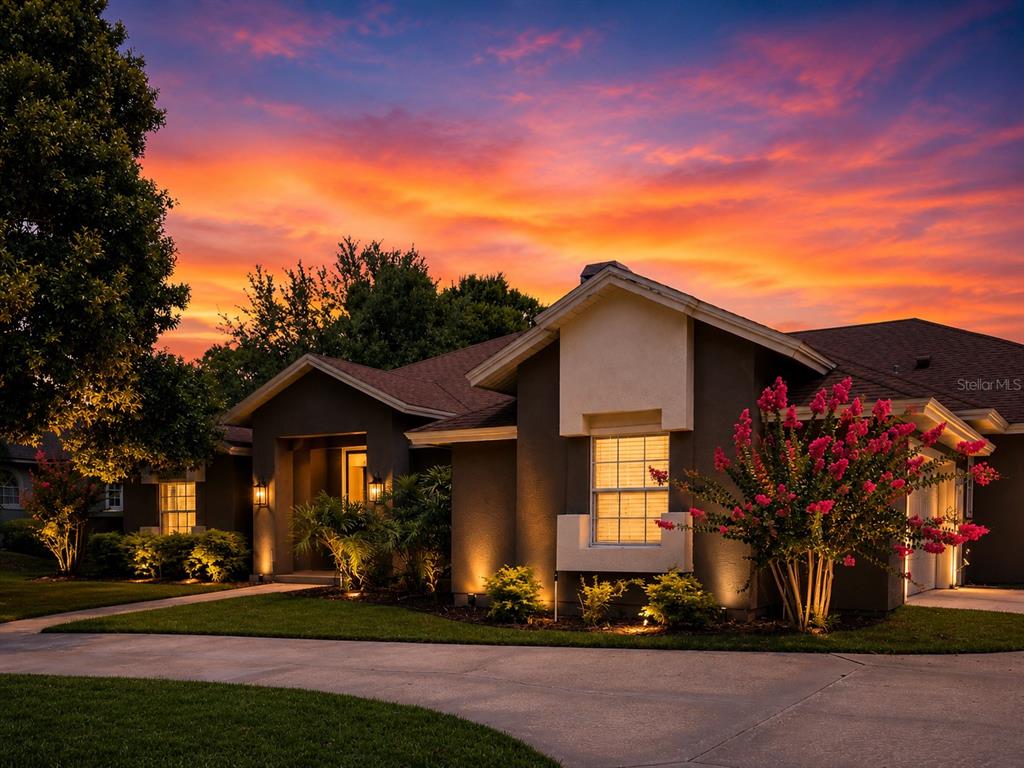 A single-story house with dark stucco walls and a vibrant sunset sky in the background — 2260 LANGLEY CIRCLE, ORLANDO, FL
