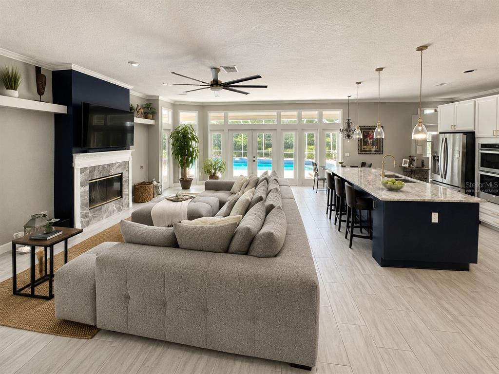 A modern kitchen features a large dark island, white cabinetry, stainless appliances, and pool views — 2260 LANGLEY CIRCLE, ORLANDO, FL