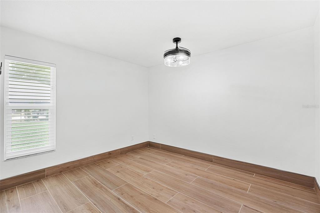 An empty room with white walls, wood-look tile flooring, and a modern ceiling light fixture — 3271 MAJESTIC OAK DRIVE, ST CLOUD, FL
