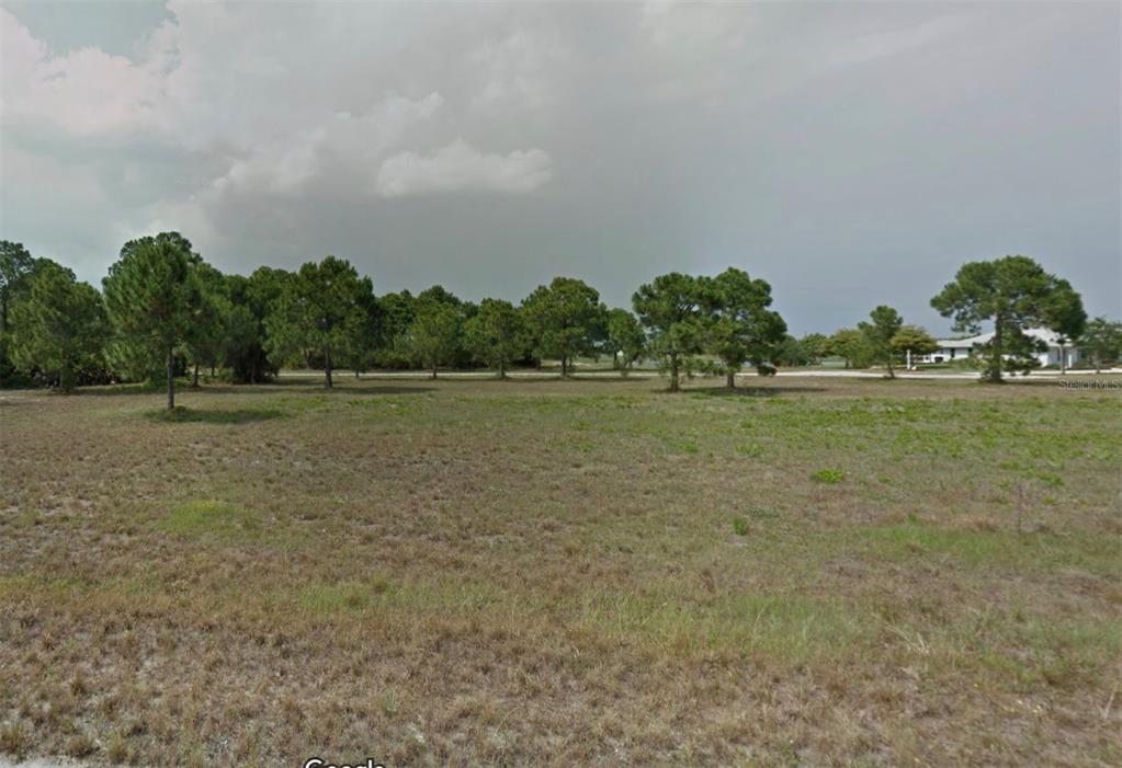 A flat, grassy vacant lot features scattered pine trees under a cloudy sky — 12 RUDDER LANE, PLACIDA, FL