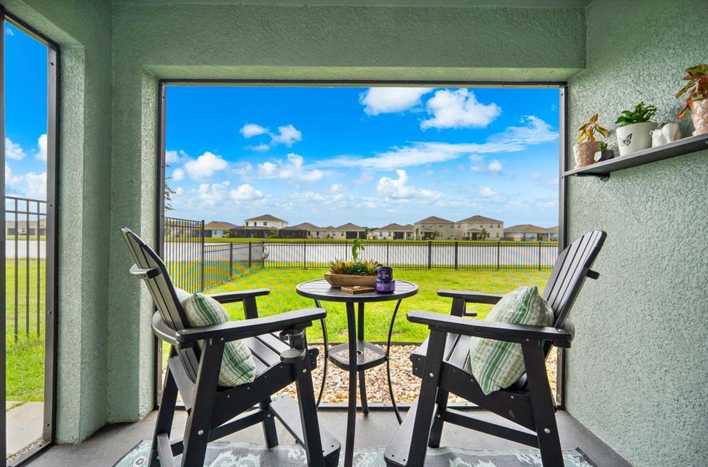 A screened-in patio features two black chairs, a small table, and a lake view — 17914 CANOPY PLACE, BRADENTON, FL