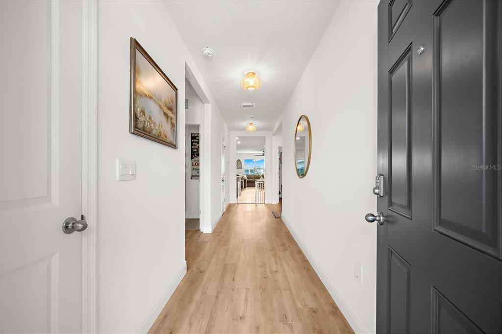 A view down a hallway with light wood flooring, white walls, and two ceiling lights — 17914 CANOPY PLACE, BRADENTON, FL
