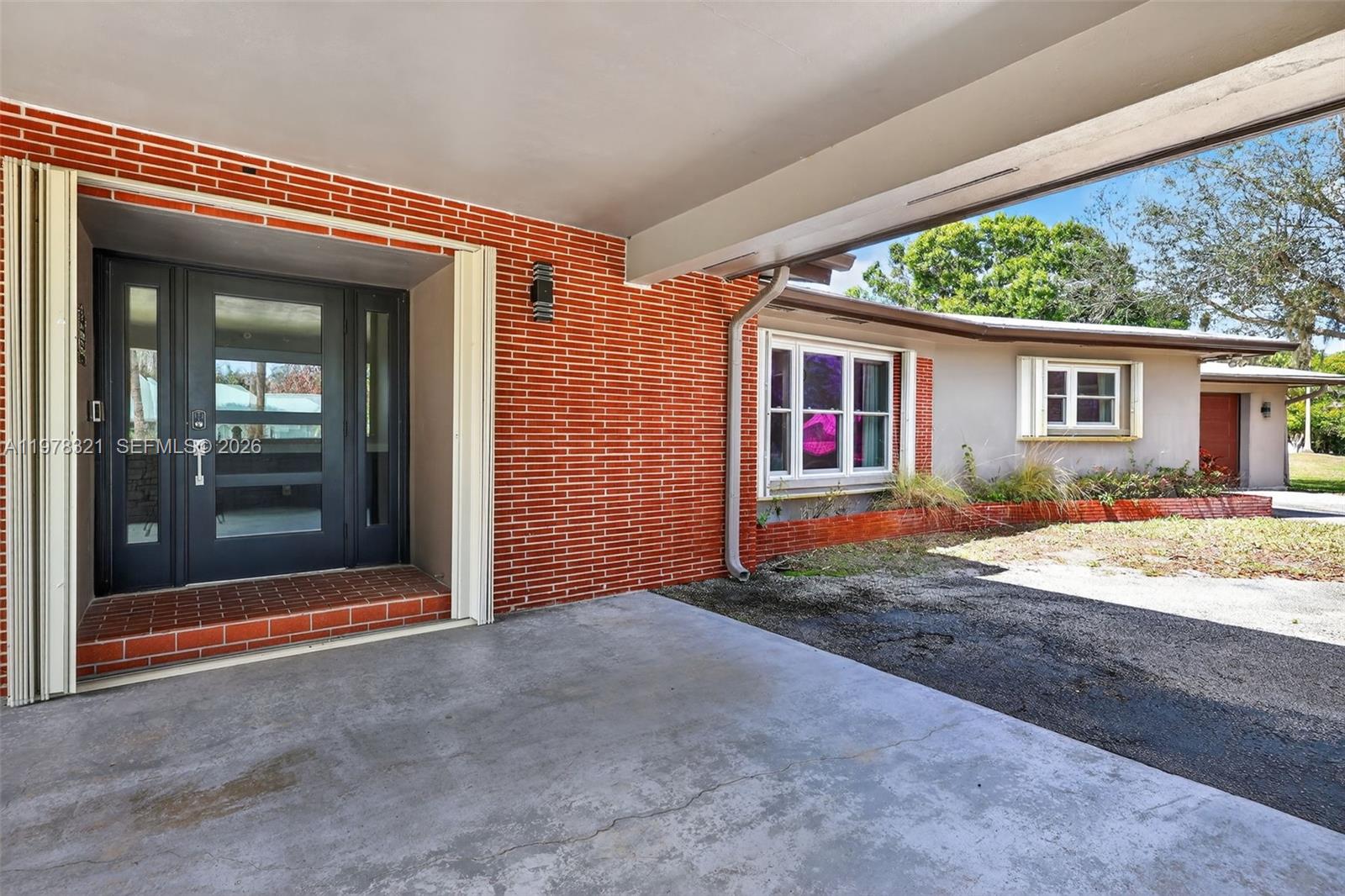 A covered carport leads to a dark gray front door on a brick-faced house — 5541 Teal Ter, Fort Pierce FL 34982, FORT PIERCE, FL