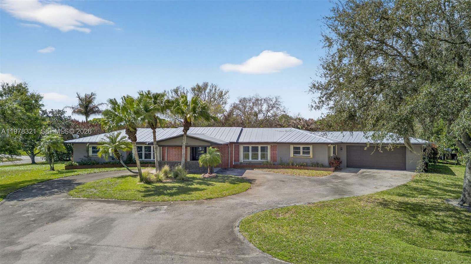 A single-story ranch-style house features a metal roof, brick accents, and a circular driveway — 5541 Teal Ter, Fort Pierce FL 34982, FORT PIERCE, FL