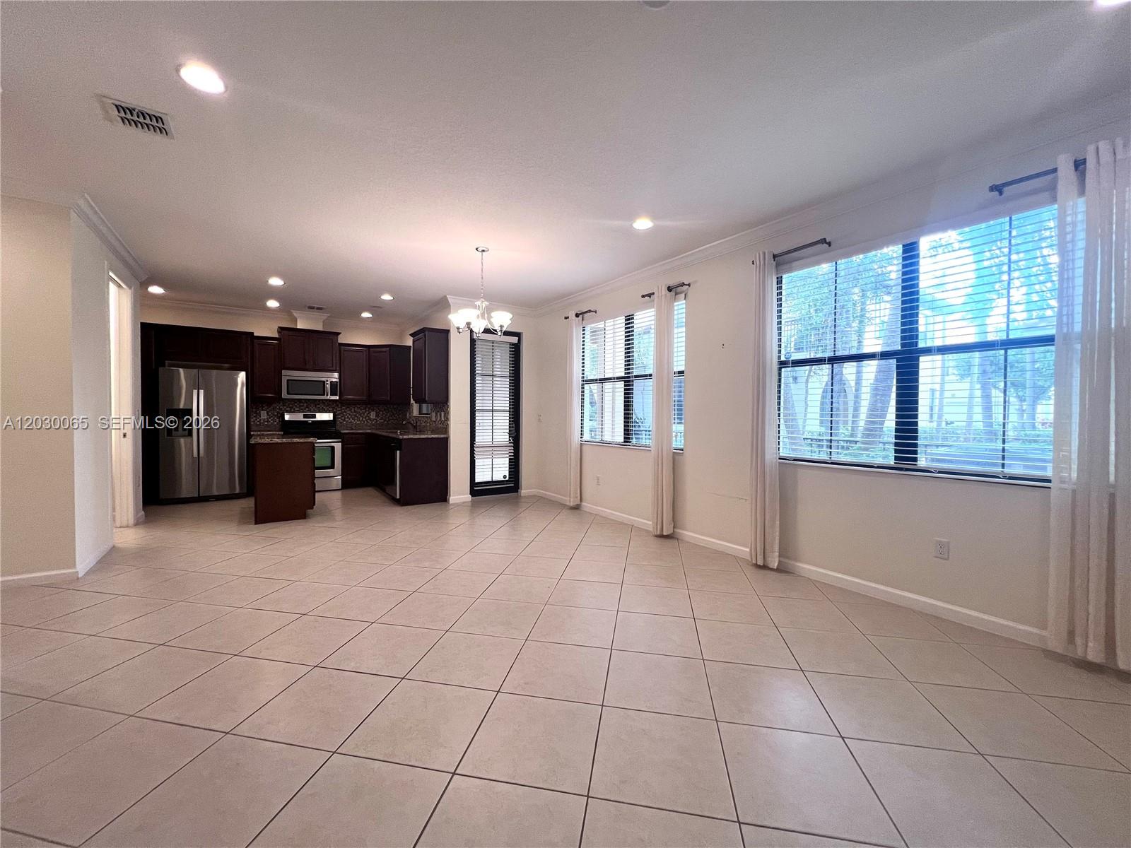 An open-concept kitchen and living area features tile flooring, dark cabinetry, and large windows — 3381 NW 125th Ave, Sunrise FL 33323, SUNRISE, FL