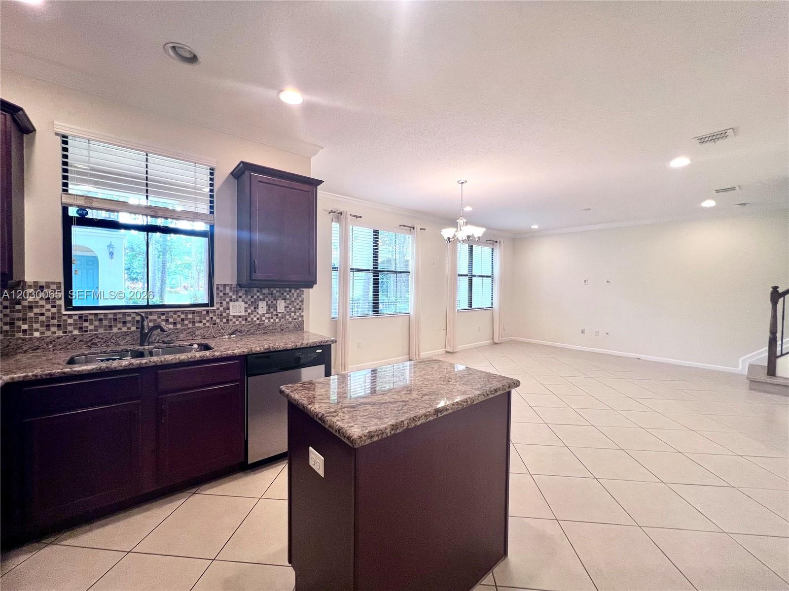 A kitchen with dark wood cabinets and granite countertops opens into a large tiled living area — 3381 NW 125th Ave, Sunrise FL 33323, SUNRISE, FL