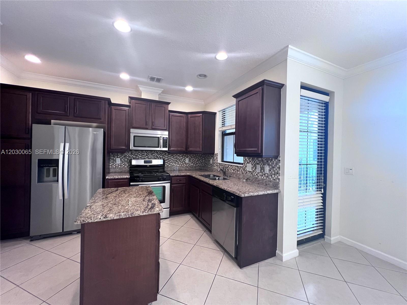 A kitchen features dark wood cabinets, granite countertops, stainless steel appliances, and tile flooring — 3381 NW 125th Ave, Sunrise FL 33323, SUNRISE, FL