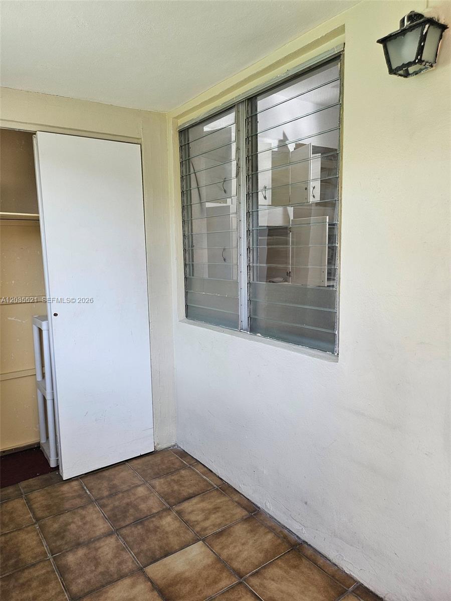 A small room features a louvered window, a white door, and brown tiled flooring — 709 NE 4th Ct # 6, Hallandale Beach FL 33009, HALLANDALE BEACH, FL
