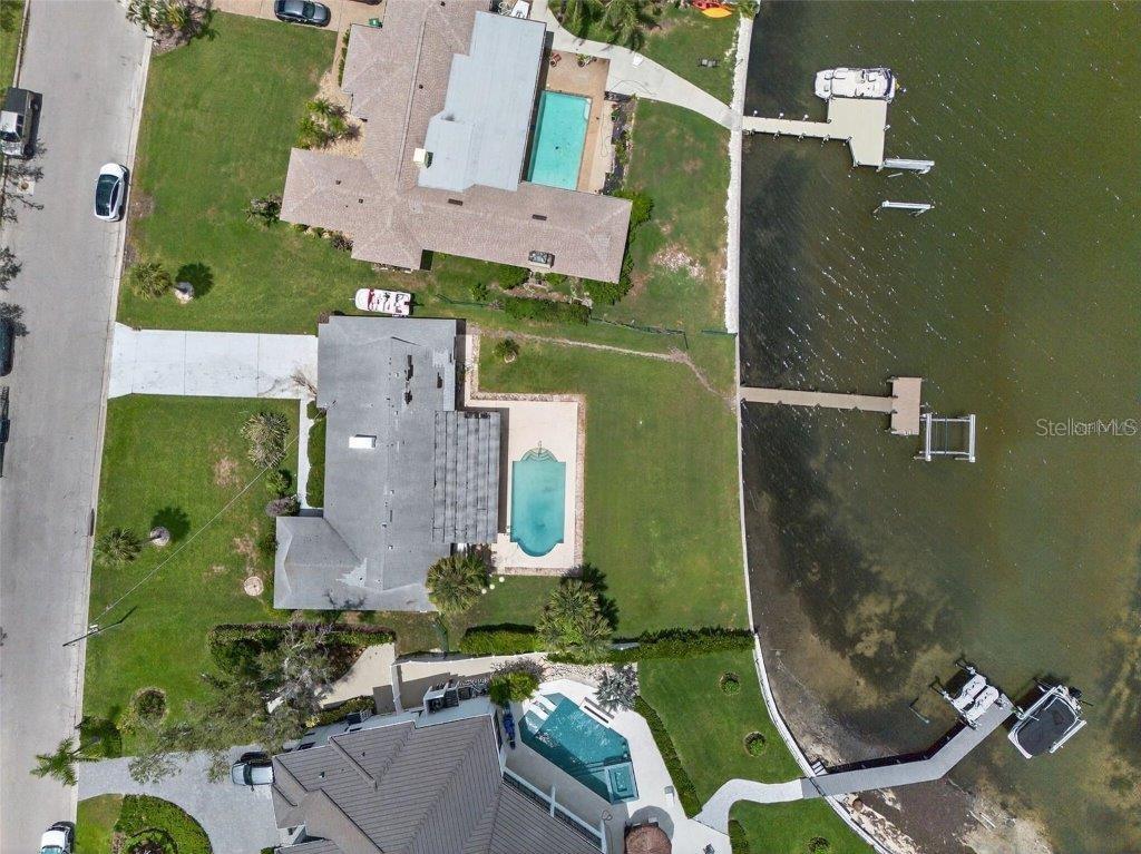 An aerial view shows three waterfront homes with private swimming pools and docks — 377 S SHORE DRIVE, SARASOTA, FL