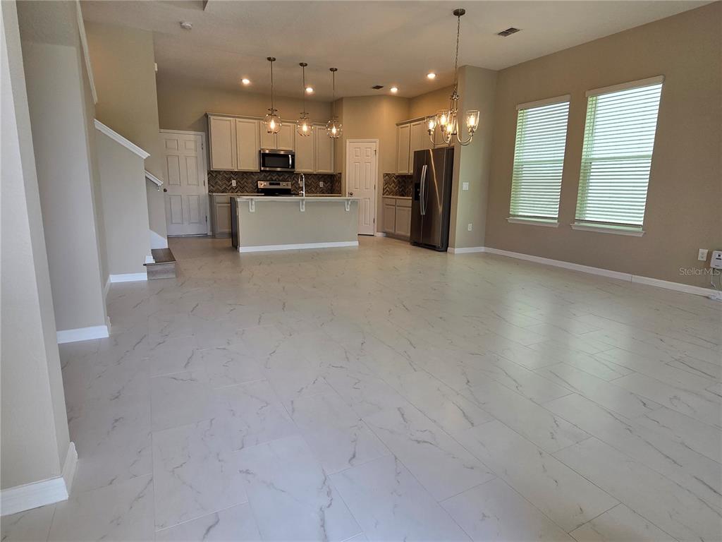 An open-concept kitchen and living area features light-colored cabinetry, stainless steel appliances, and tile flooring — 2081 STANDING ROCK CIRCLE, WINTER GARDEN, FL