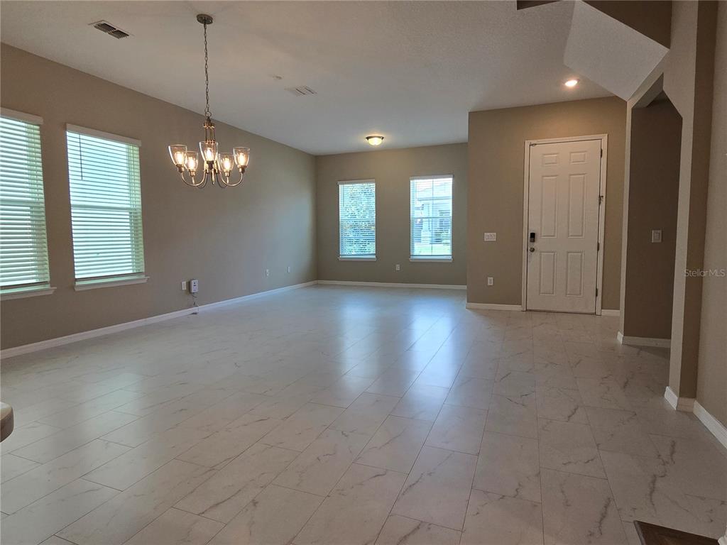 An open-concept room features light-colored tile flooring, beige walls, and a multi-light chandelier — 2081 STANDING ROCK CIRCLE, WINTER GARDEN, FL