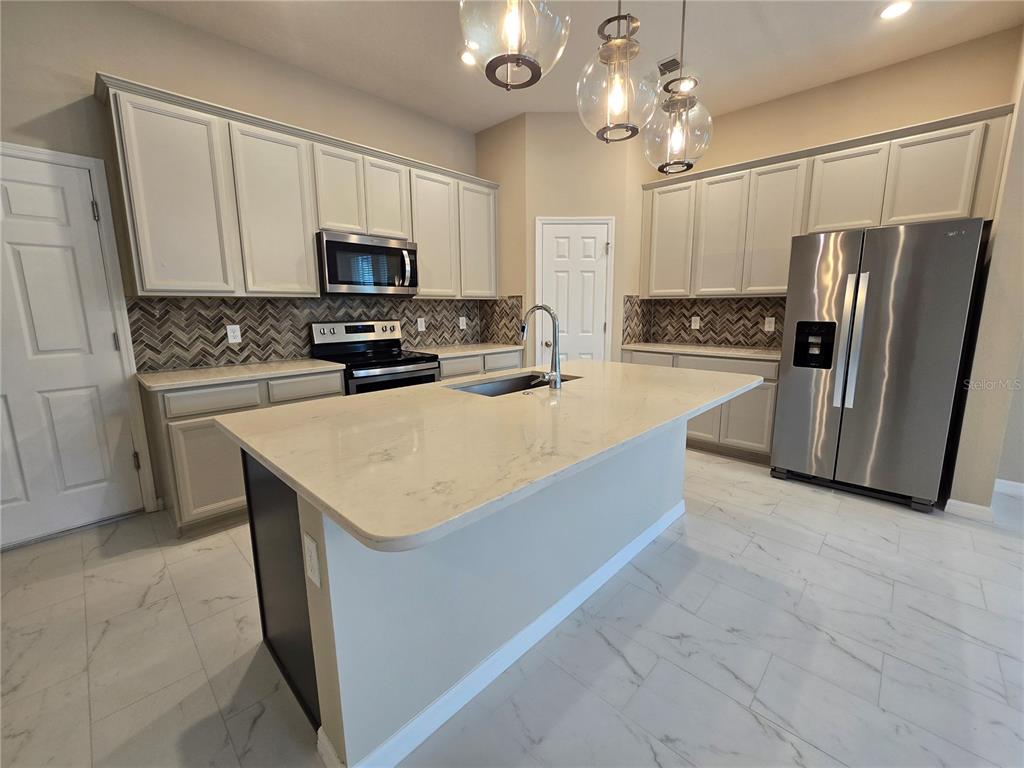 A kitchen features light-colored cabinets, a central island with a sink, and stainless steel appliances — 2081 STANDING ROCK CIRCLE, WINTER GARDEN, FL