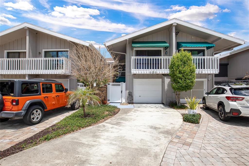 A two-story residential building with a garage, balcony, and two parked cars in front — 121 LAGOON COURT, NEW SMYRNA BEACH, FL
