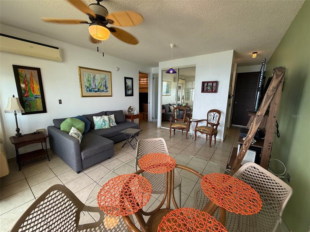 A living and dining area features a gray sectional sofa, tile flooring, and a ceiling fan — Condo Pelican Reef APT 302 UNIT 302, RINCON, PR