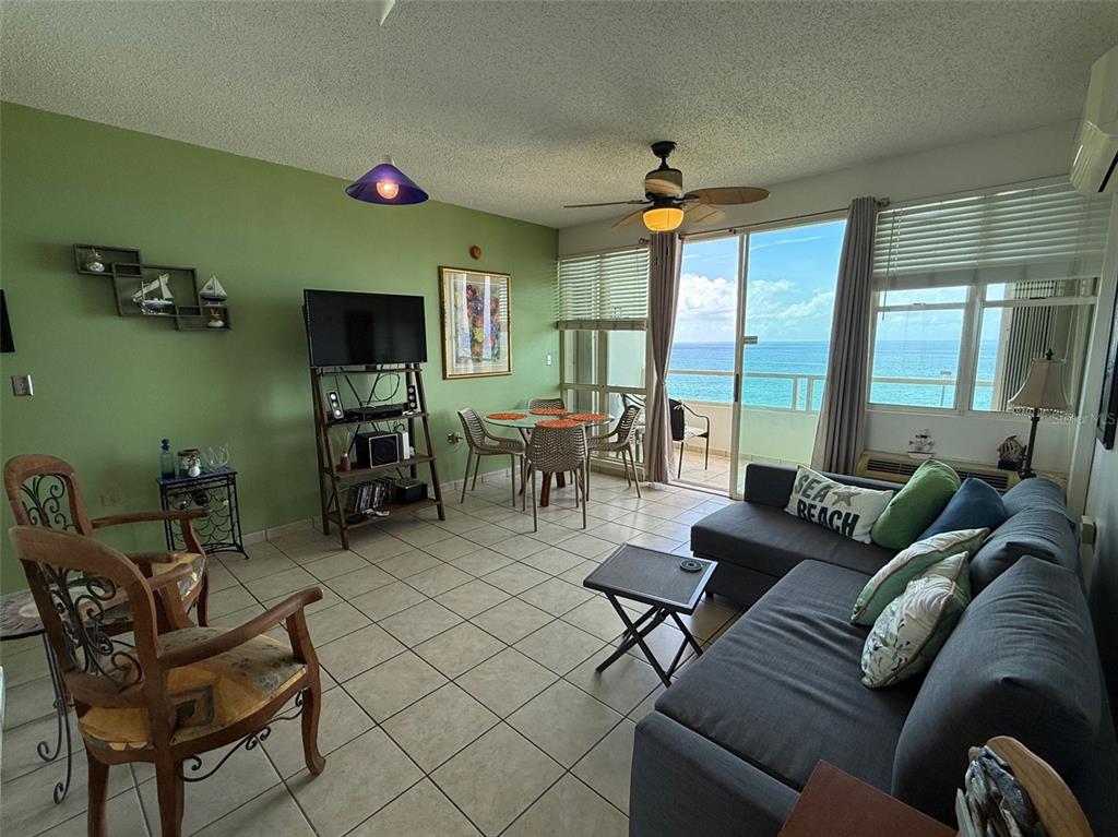 A living room with tile floors, a green wall, and a balcony overlooking the ocean — Condo Pelican Reef APT 302 UNIT 302, RINCON, PR