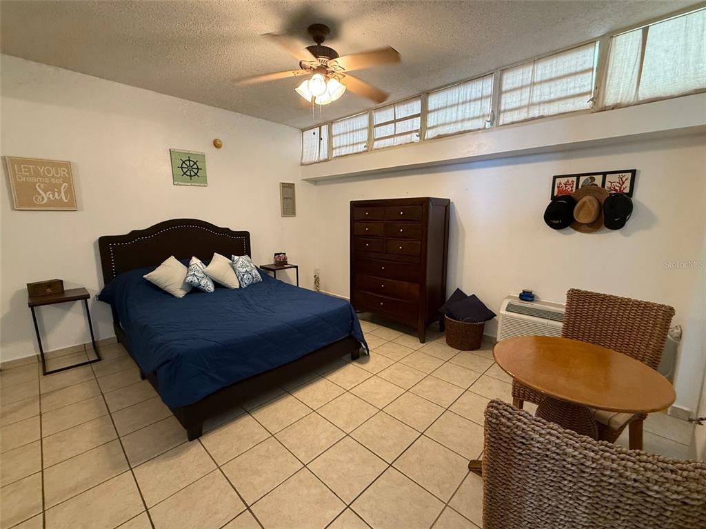 A bedroom features a bed, a tall dresser, a small table with chairs, and tile flooring — Condo Pelican Reef APT 302 UNIT 302, RINCON, PR