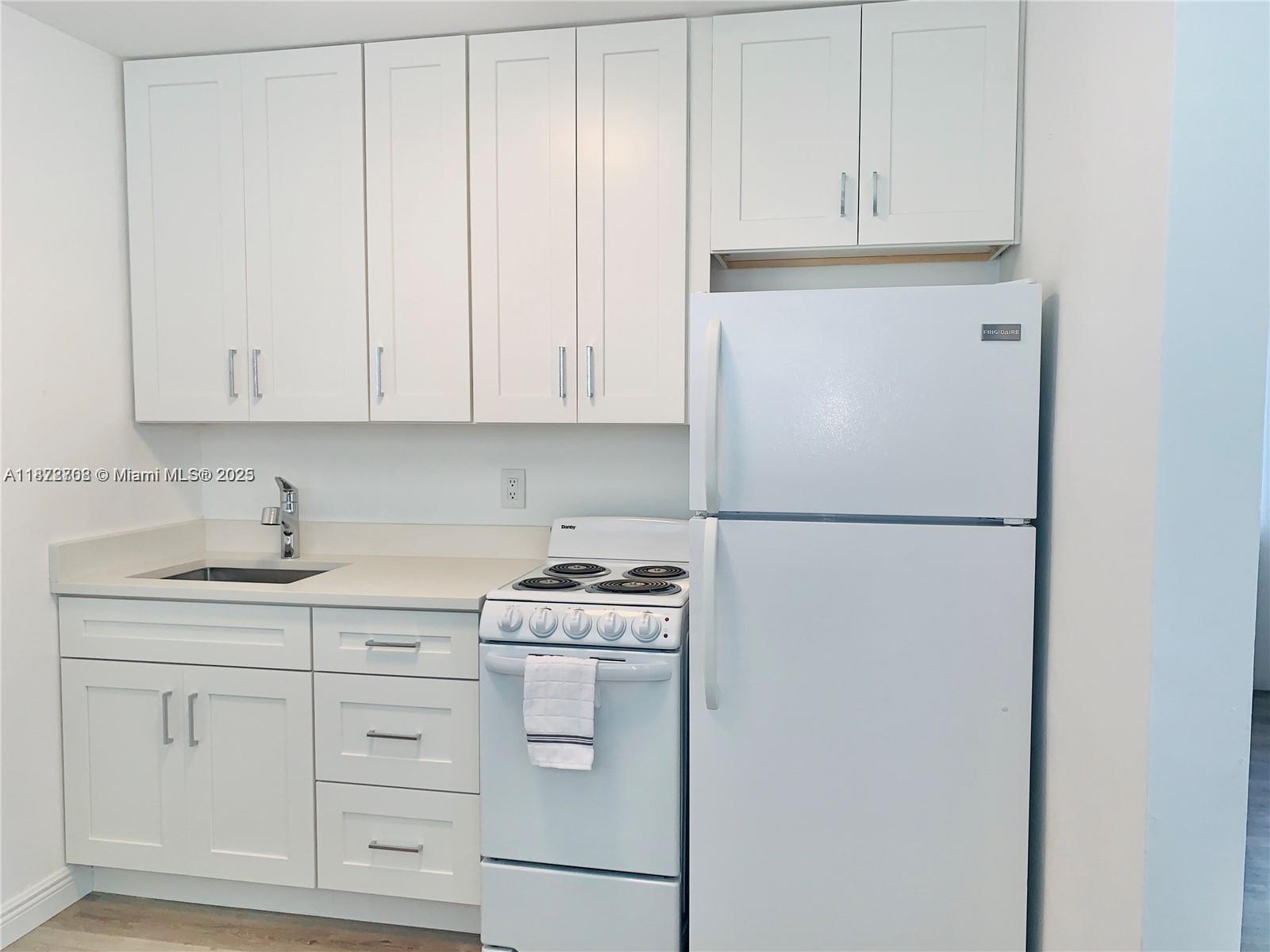 A small kitchen features white cabinets, a white stove, and a white refrigerator — 116 SE 9th Ct, Hallandale Beach FL 33009, HALLANDALE BEACH, FL