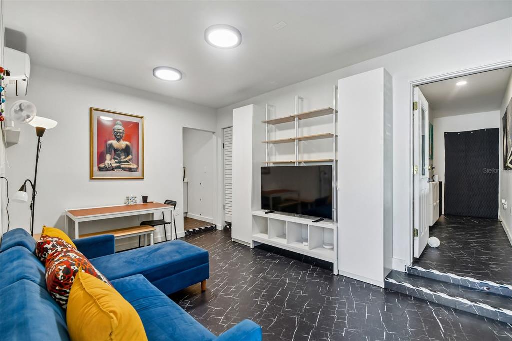 A living room features a blue sectional sofa, a television unit, and dark marble-patterned flooring — 2013 LOCH BERRY ROAD, WINTER PARK, FL