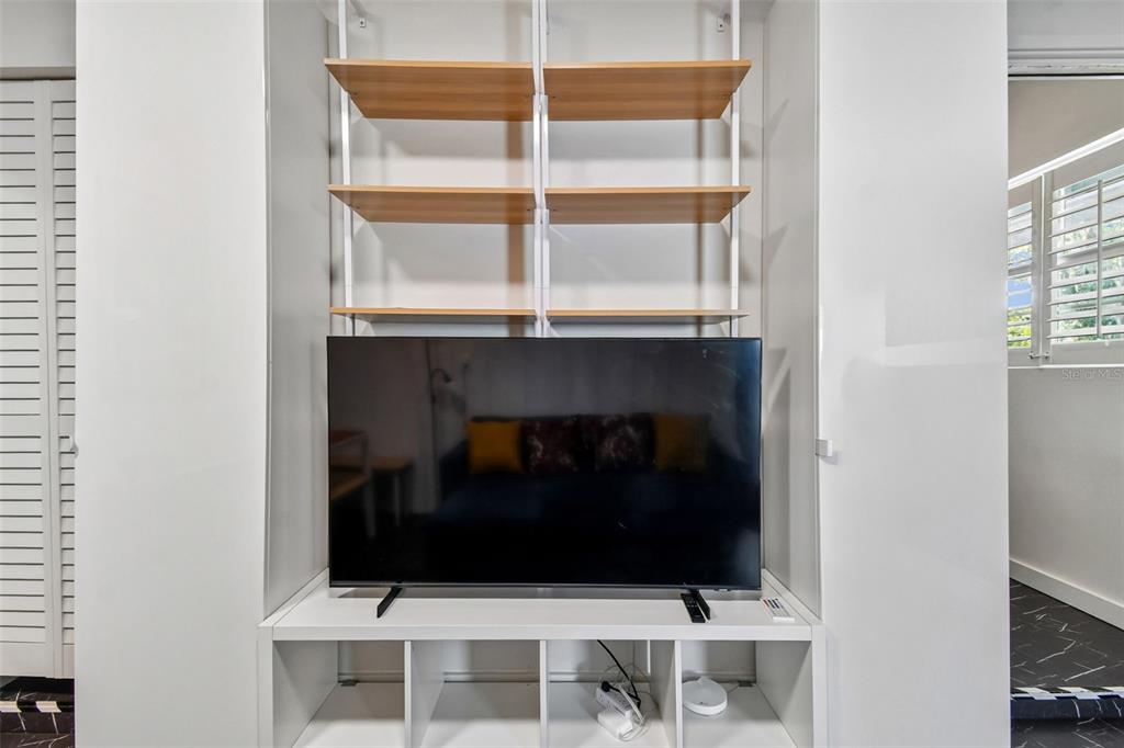 A television sits on a white storage unit with open shelving against a white wall — 2013 LOCH BERRY ROAD, WINTER PARK, FL