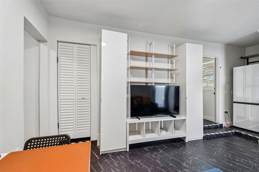 A room features a white media unit with open shelving, a television, and black flooring — 2013 LOCH BERRY ROAD, WINTER PARK, FL