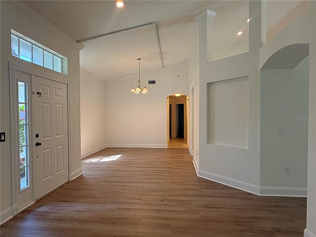An entryway leads into a living area with light wood-look flooring and a vaulted ceiling — 14832 HERONGLEN DRIVE, LITHIA, FL