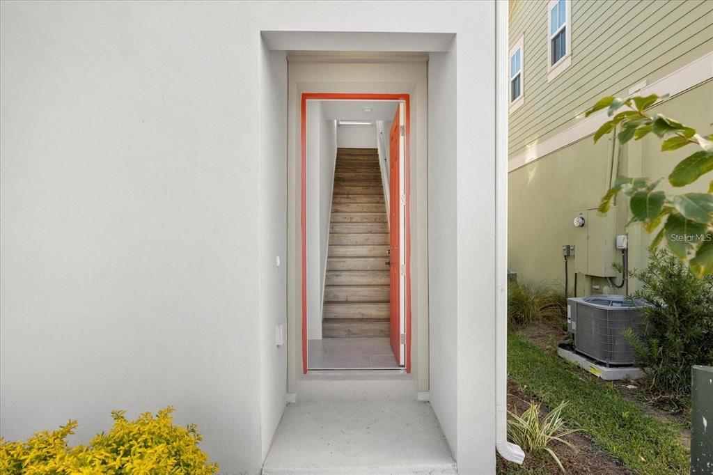 An exterior view of a doorway leading to an interior staircase with wood-look flooring — 10535 MARCONI AVENUE, ORLANDO, FL