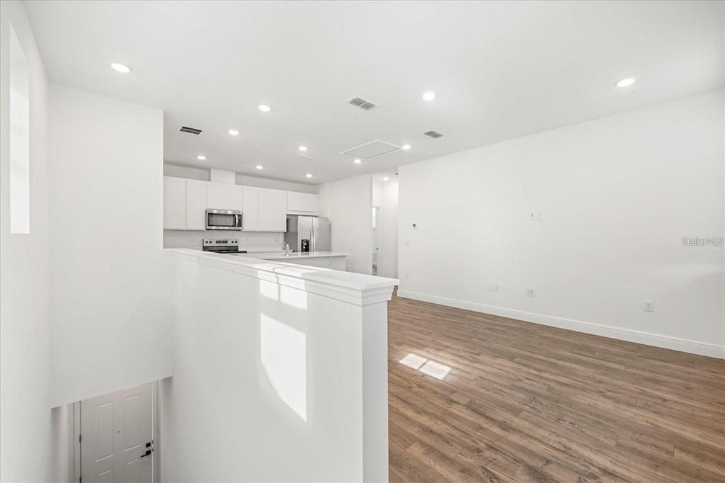 An open-concept kitchen and living area with white cabinetry and wood-look flooring — 10535 MARCONI AVENUE, ORLANDO, FL