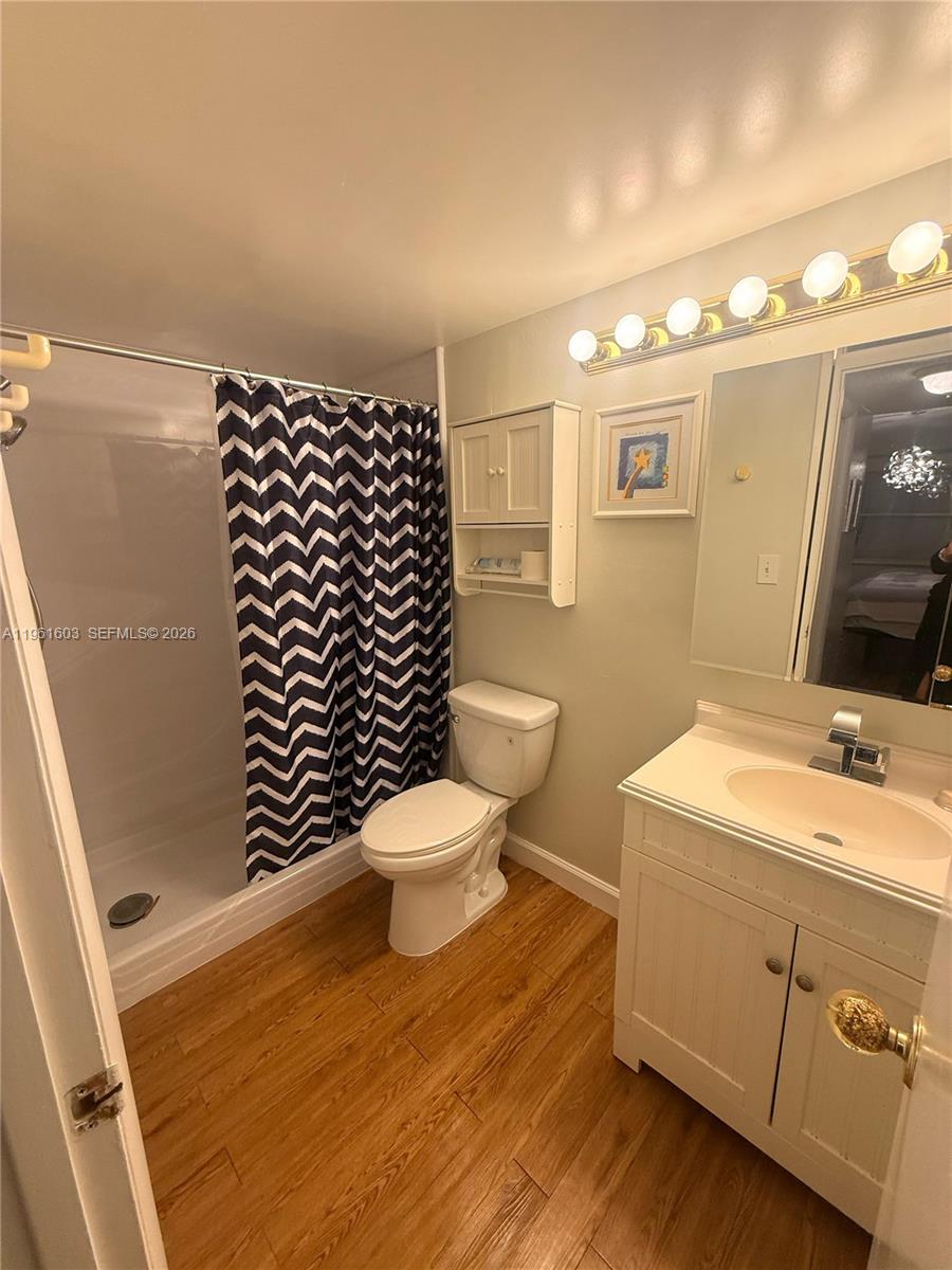 A bathroom features a shower with a chevron curtain, a toilet, and a white vanity — 5180 E Sabal Palm Blvd # 133, Tamarac FL 33319, TAMARAC, FL