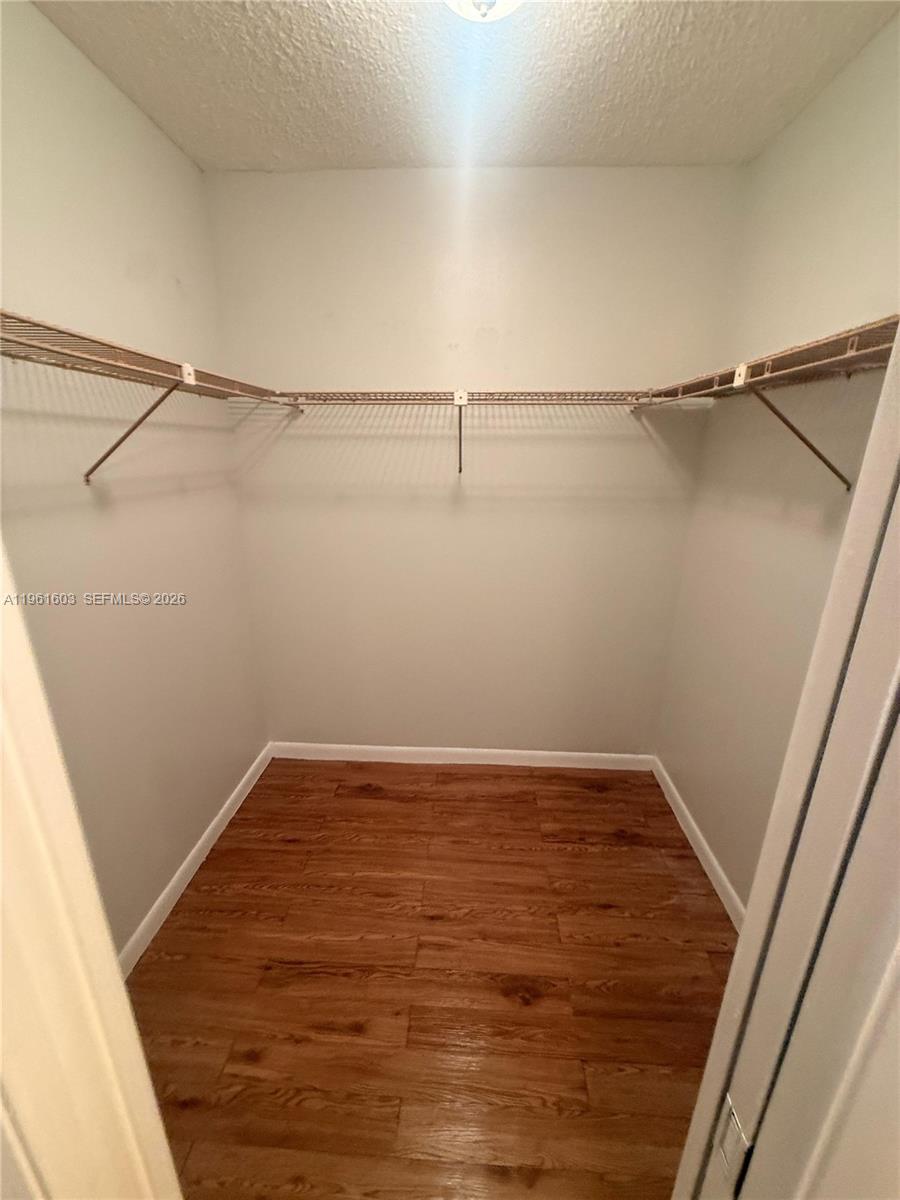 A walk-in closet features wire shelving, light-colored walls, and wood-look flooring — 5180 E Sabal Palm Blvd # 133, Tamarac FL 33319, TAMARAC, FL