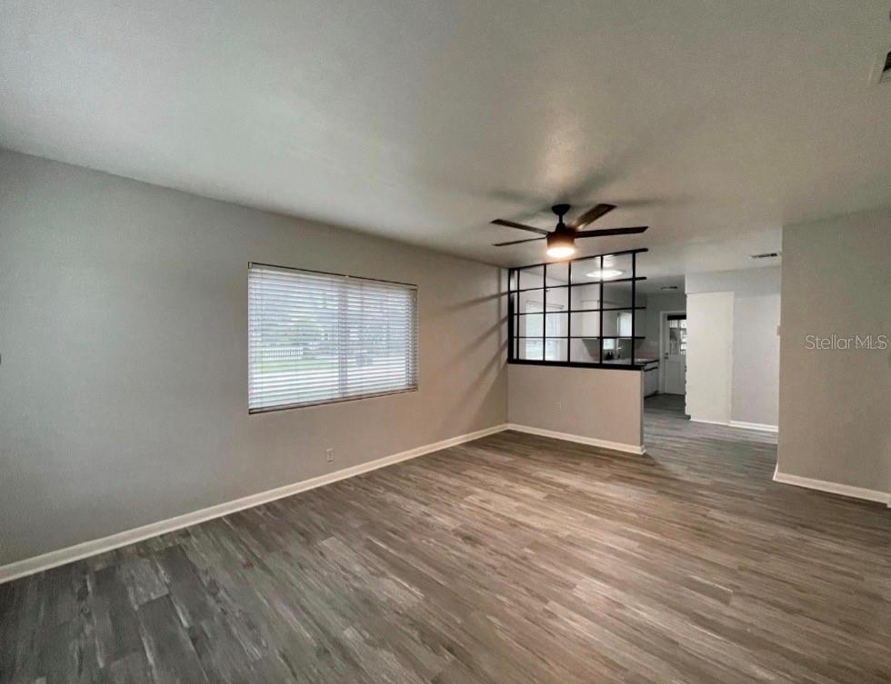 A living room with gray walls, wood-look flooring, a ceiling fan, and a black room divider — 1751 WESTCHESTER AVENUE, WINTER PARK, FL