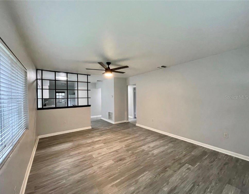 A living room with light gray walls, wood-look flooring, and a black-framed interior room divider — 1751 WESTCHESTER AVENUE, WINTER PARK, FL
