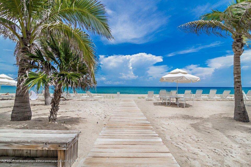 A wooden boardwalk leads through a sandy beach area with palm trees and lounge chairs — 170 N Ocean Boulevard # 305, Palm Beach FL 33480, PALM BEACH, FL