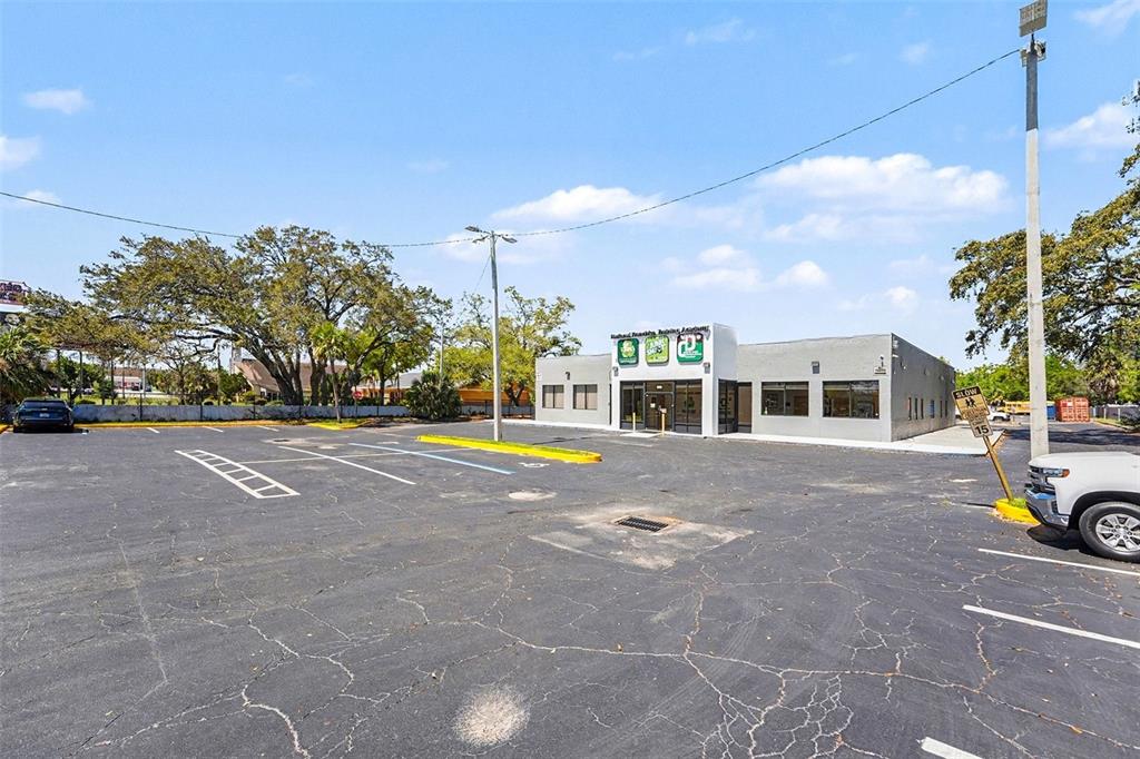 A single-story commercial building with a large asphalt parking lot under a blue sky — 2304 E BUSCH BOULEVARD, TAMPA, FL