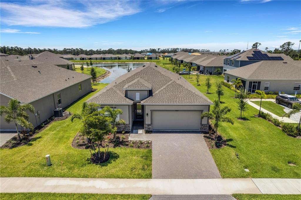 An aerial view shows a single-story suburban house with a paved driveway and a pond — 16807 CAYO KEY DRIVE, PORT CHARLOTTE, FL