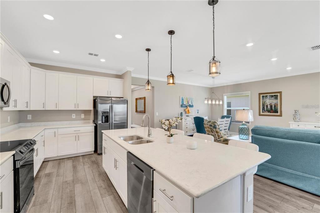 A kitchen with white cabinets, a quartz island, and stainless steel appliances opens to living — 16807 CAYO KEY DRIVE, PORT CHARLOTTE, FL