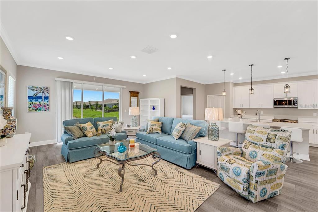 A living room with blue sofas, a patterned armchair, and an open kitchen with white cabinets — 16807 CAYO KEY DRIVE, PORT CHARLOTTE, FL