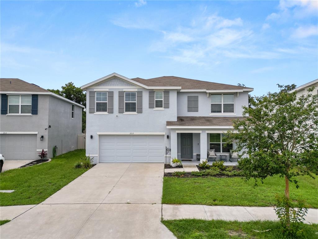 A two-story light blue house with a two-car garage and a front porch — 3715 CAPRI COAST DRIVE, PLANT CITY, FL