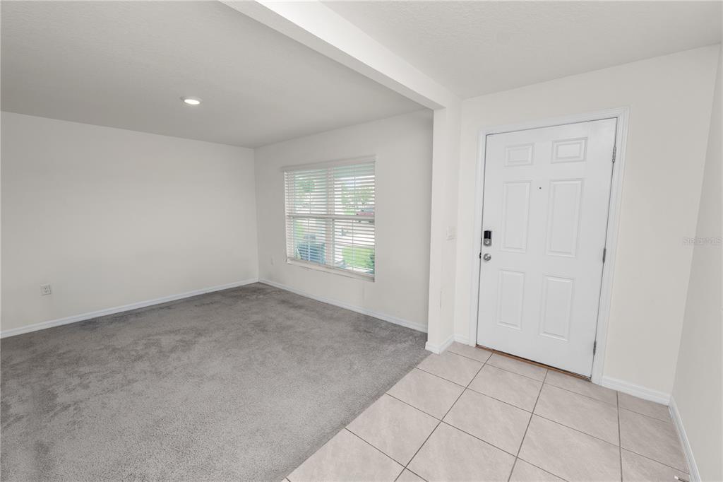 A room with gray carpet and a white front door with tile flooring — 3715 CAPRI COAST DRIVE, PLANT CITY, FL