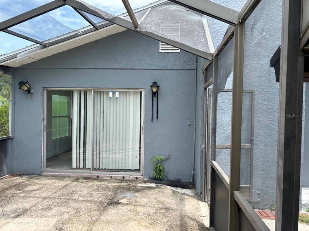 A concrete patio sits outside a sliding glass door beneath a screened-in enclosure — 1169 KINGSLEY STREET, CLEARWATER, FL