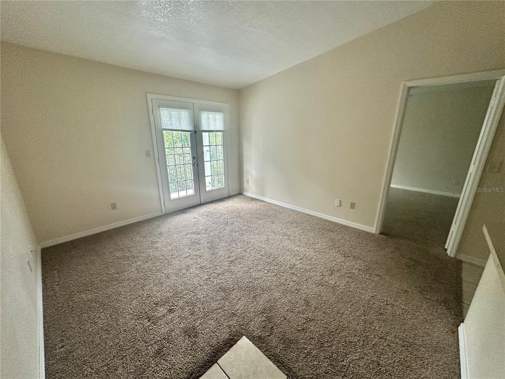 An empty room with beige carpet, light-colored walls, and a set of French doors — 2550 N ALAFAYA TRAIL UNIT 10305, ORLANDO, FL